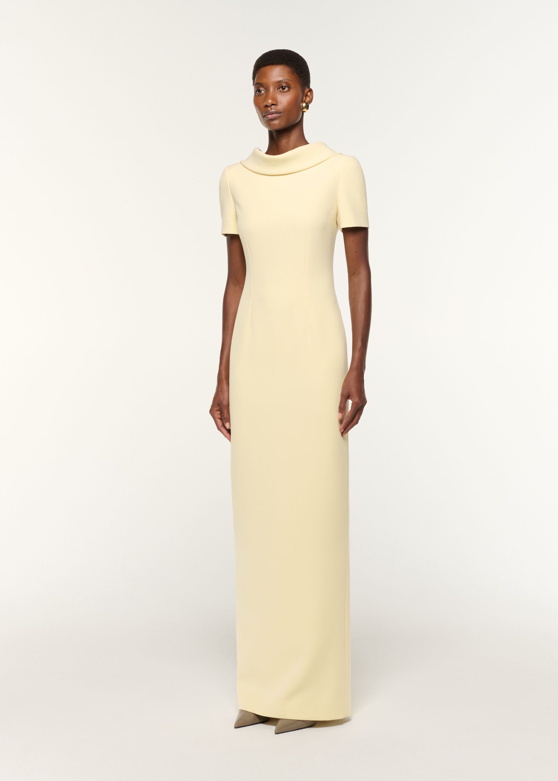 Side view of a model wearing the Collared Crepe Gown in Yellow