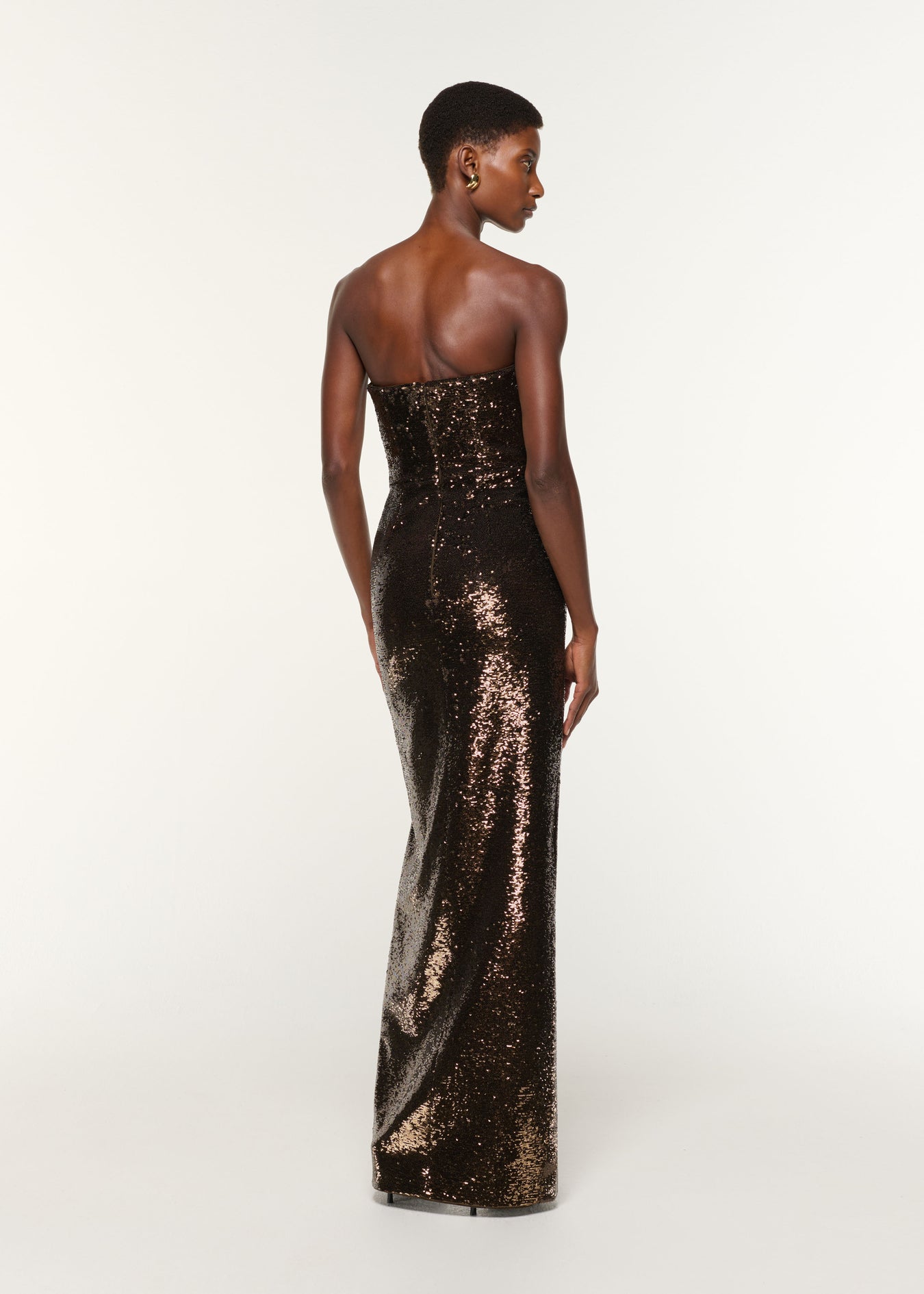 Back view of a model wearing the Strapless Sequin Buckle Gown in Bronze