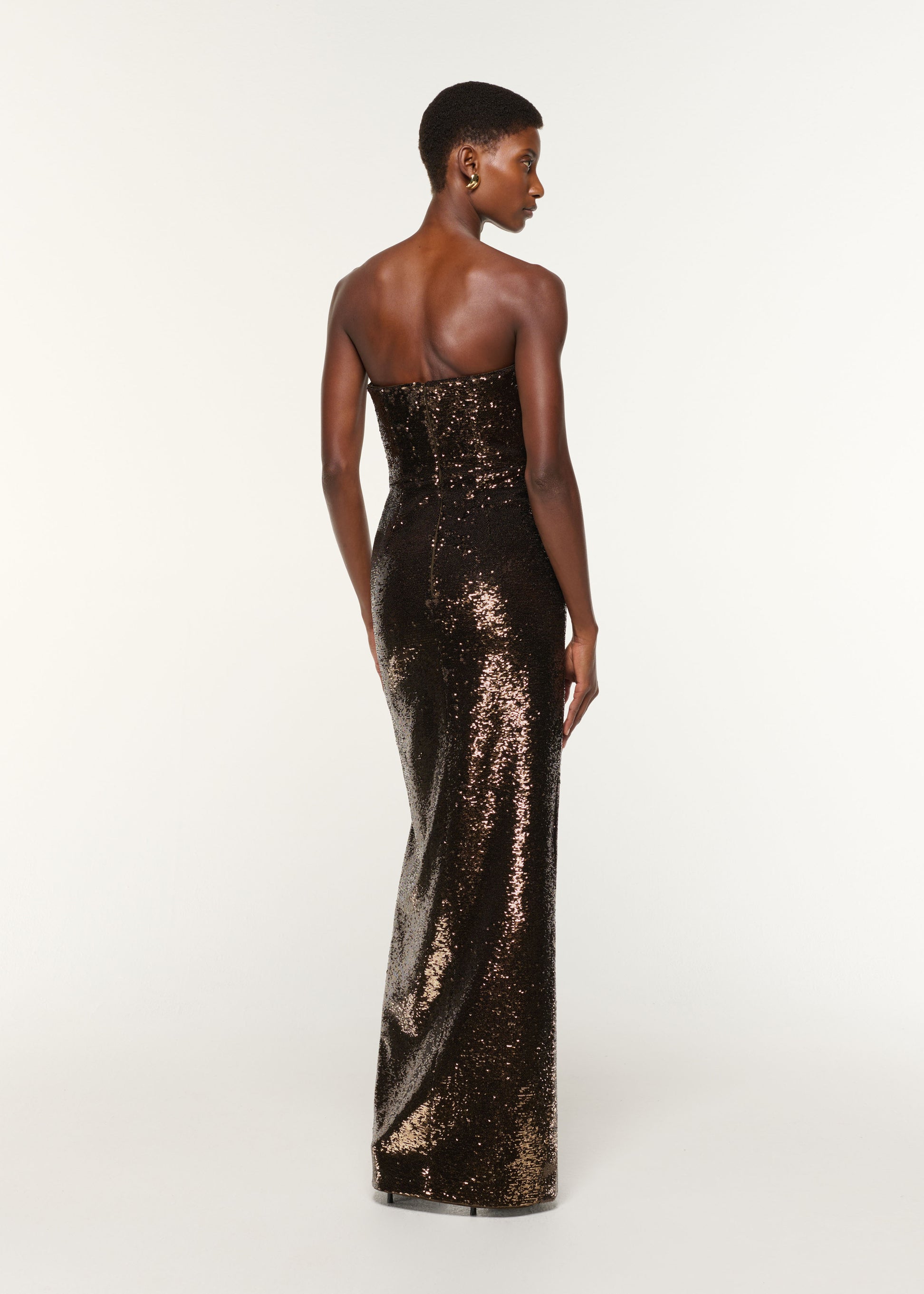 Back view of a model wearing the Strapless Sequin Buckle Gown in Bronze