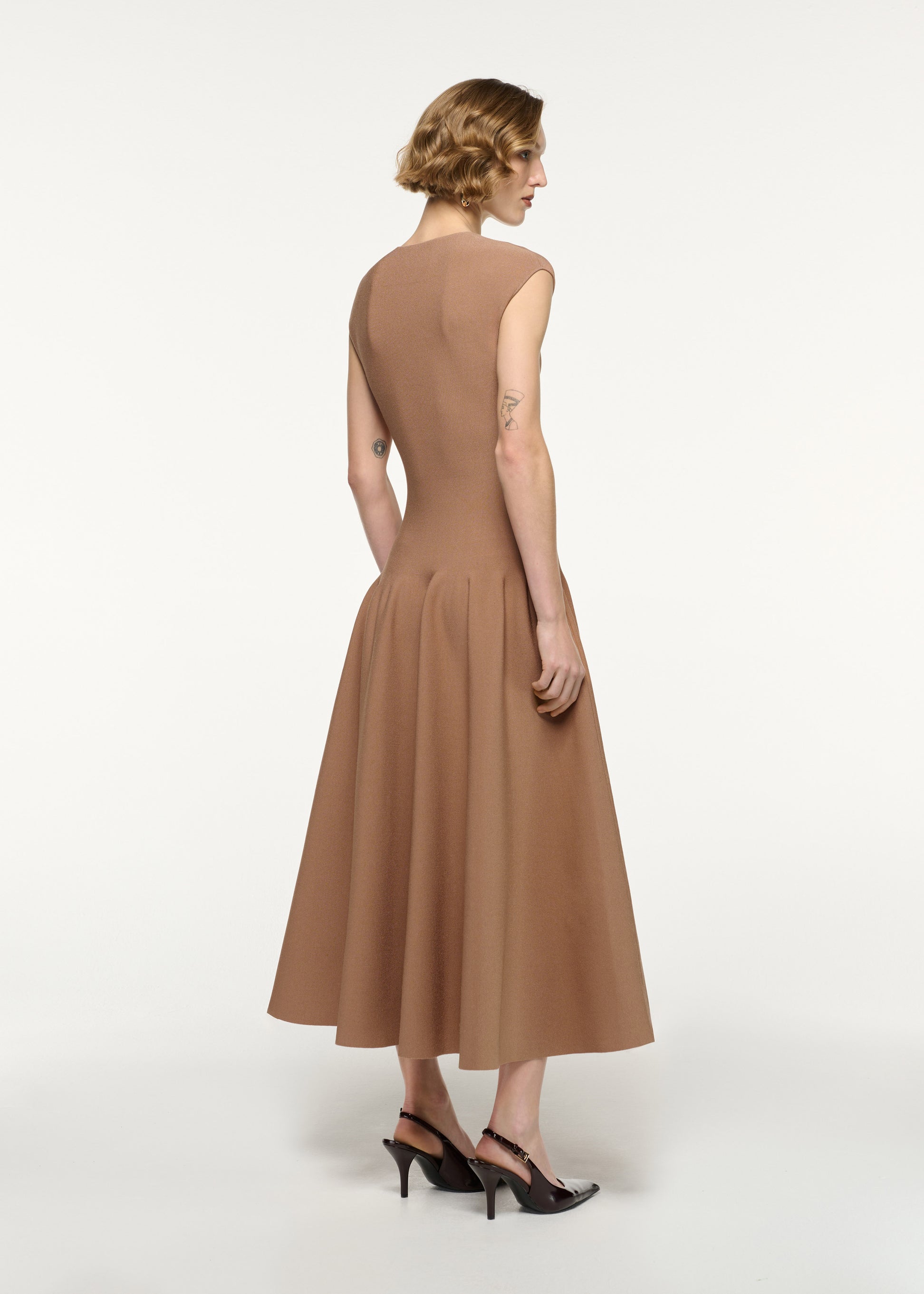 Back view of a model wearing the Pebble Trimmed Knit Dress in Camel