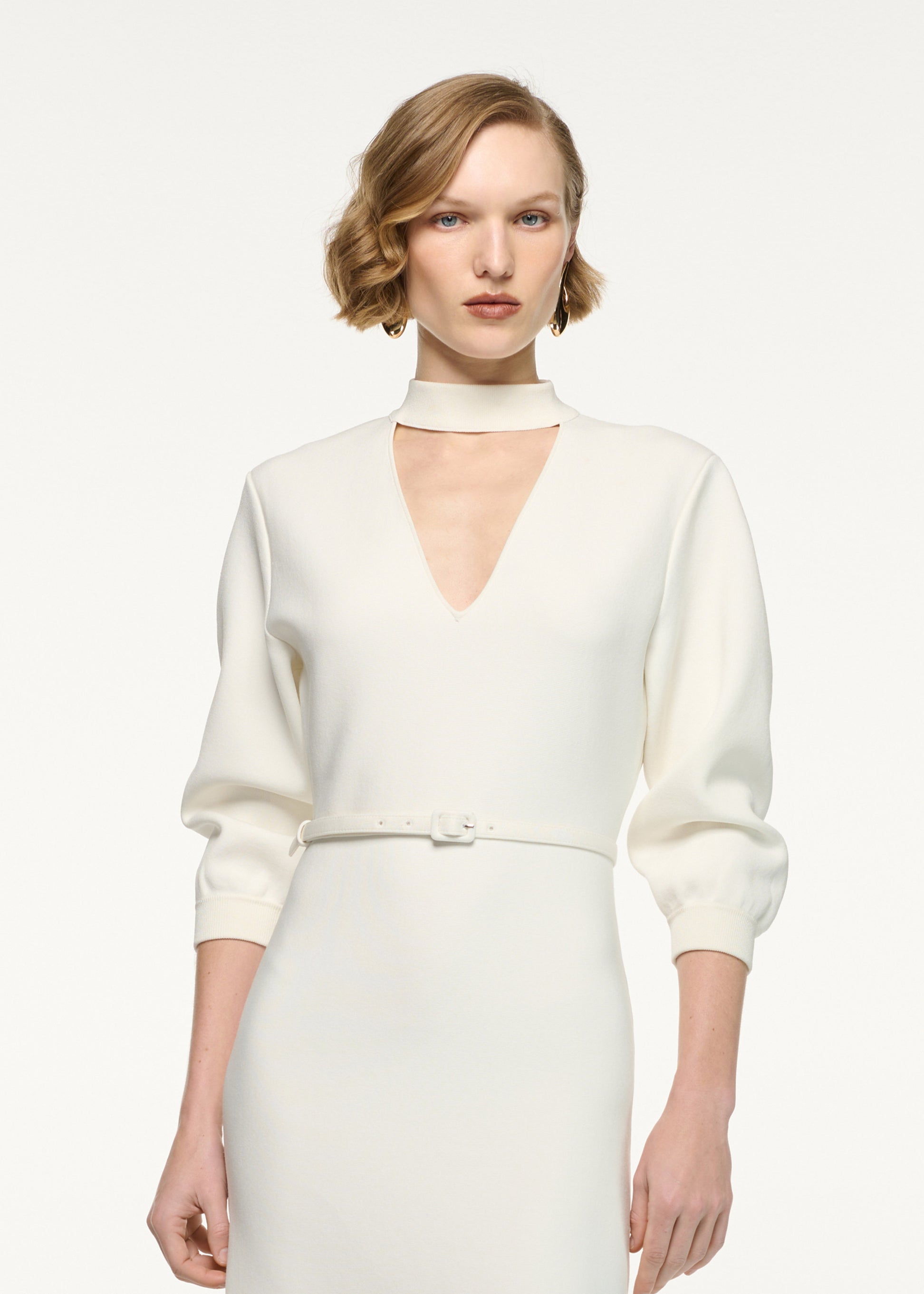 Close up of a model wearing the Belted Blouson Knit Midi Dress in Cream 
