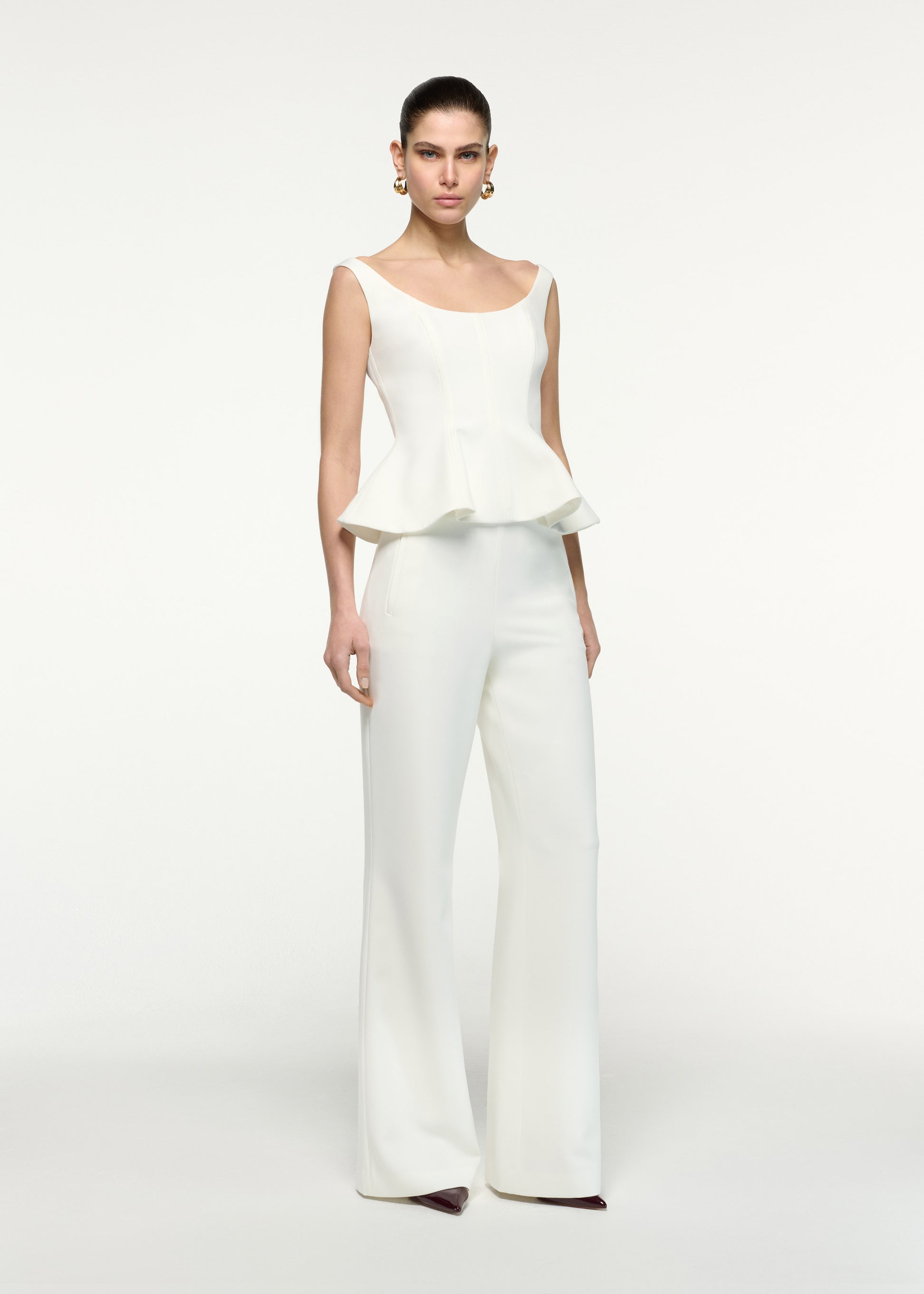 Side view of a model wearing the Crepe Peplum Top in Cream