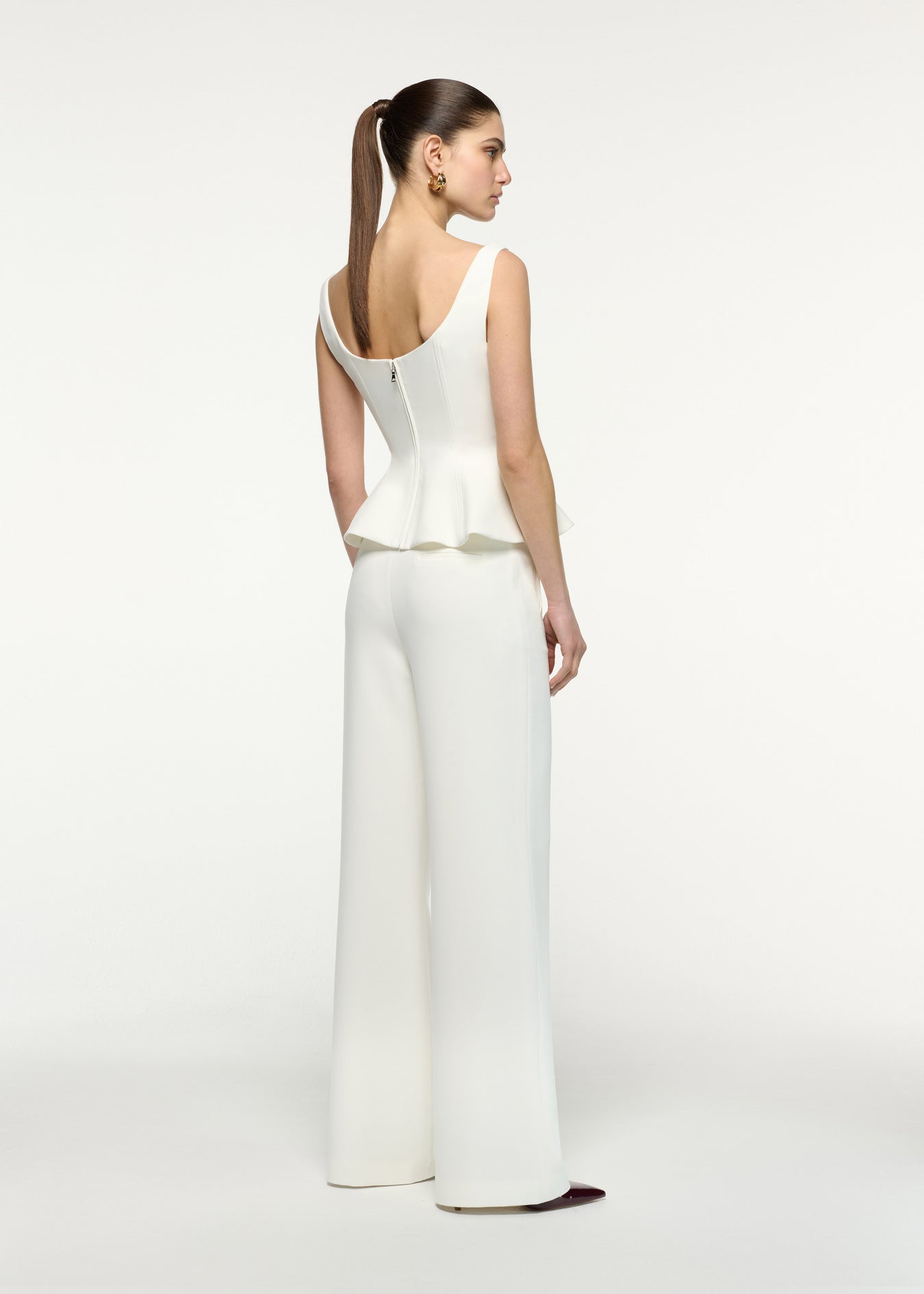 Back view of a model wearing the Crepe Peplum Top in Cream