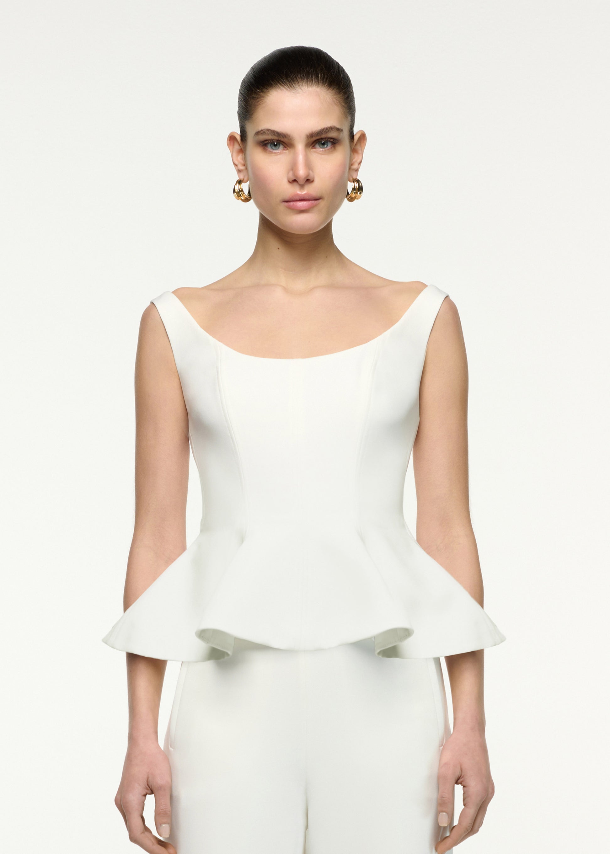Close up of a model wearing the Crepe Peplum Top in Cream