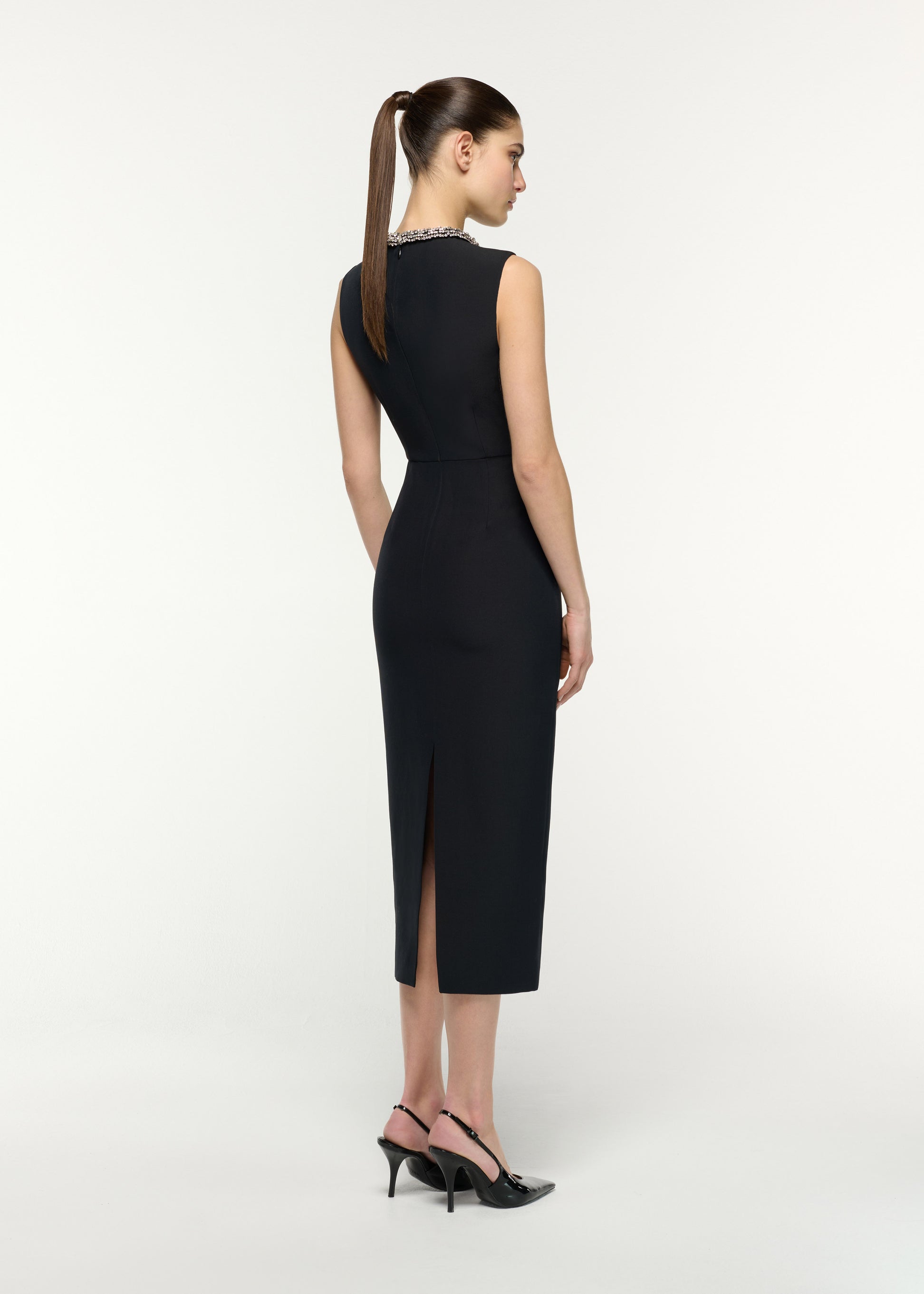 Back view of a model wearing the Crystal Neck Trimmed Asymmetric Peplum Midi Dress in Black 