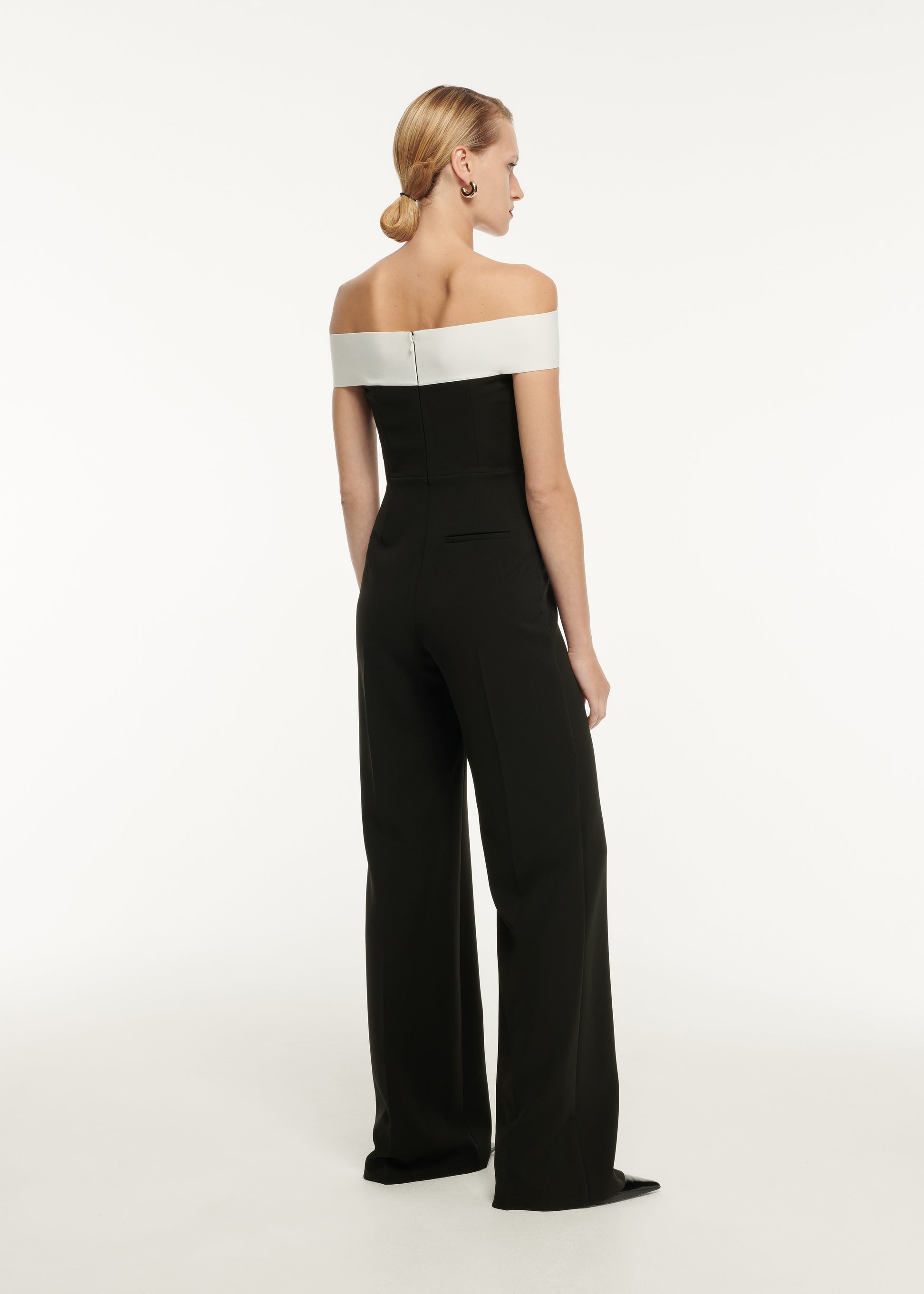 The back of a woman wearing the Off The Shoulder Stretch Cady Jumpsuit