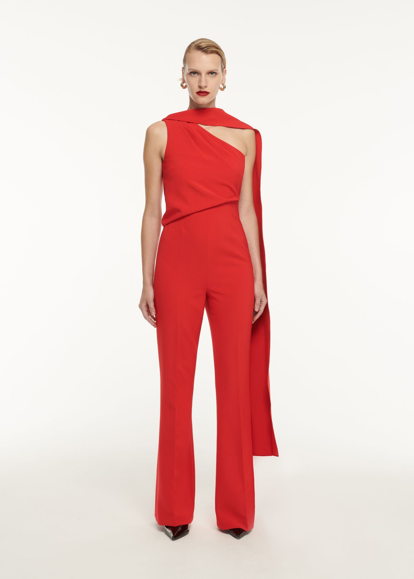 A woman wearing the Asymmetric Crepe Jumpsuit in Red