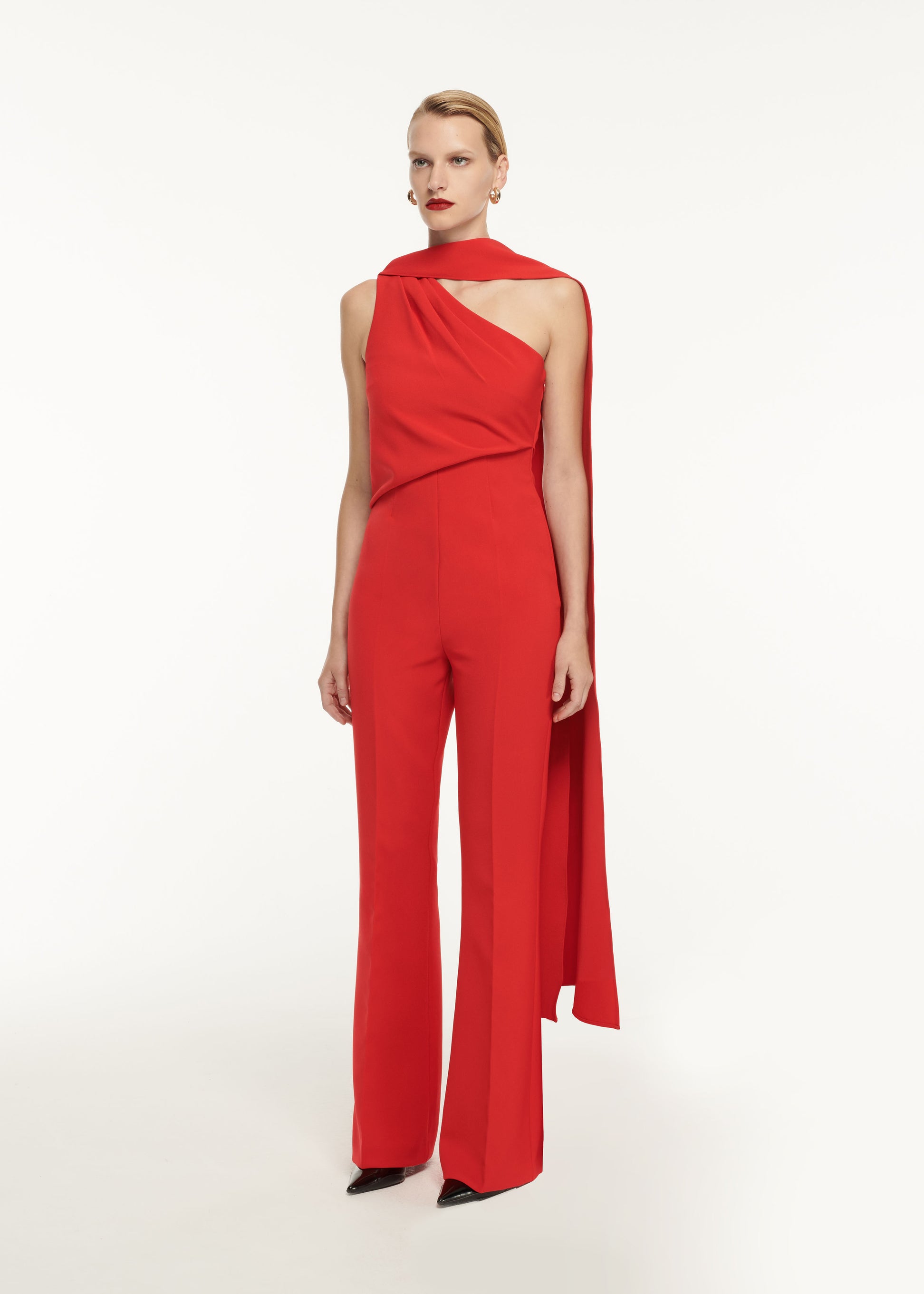 A woman wearing the Asymmetric Crepe Jumpsuit Red