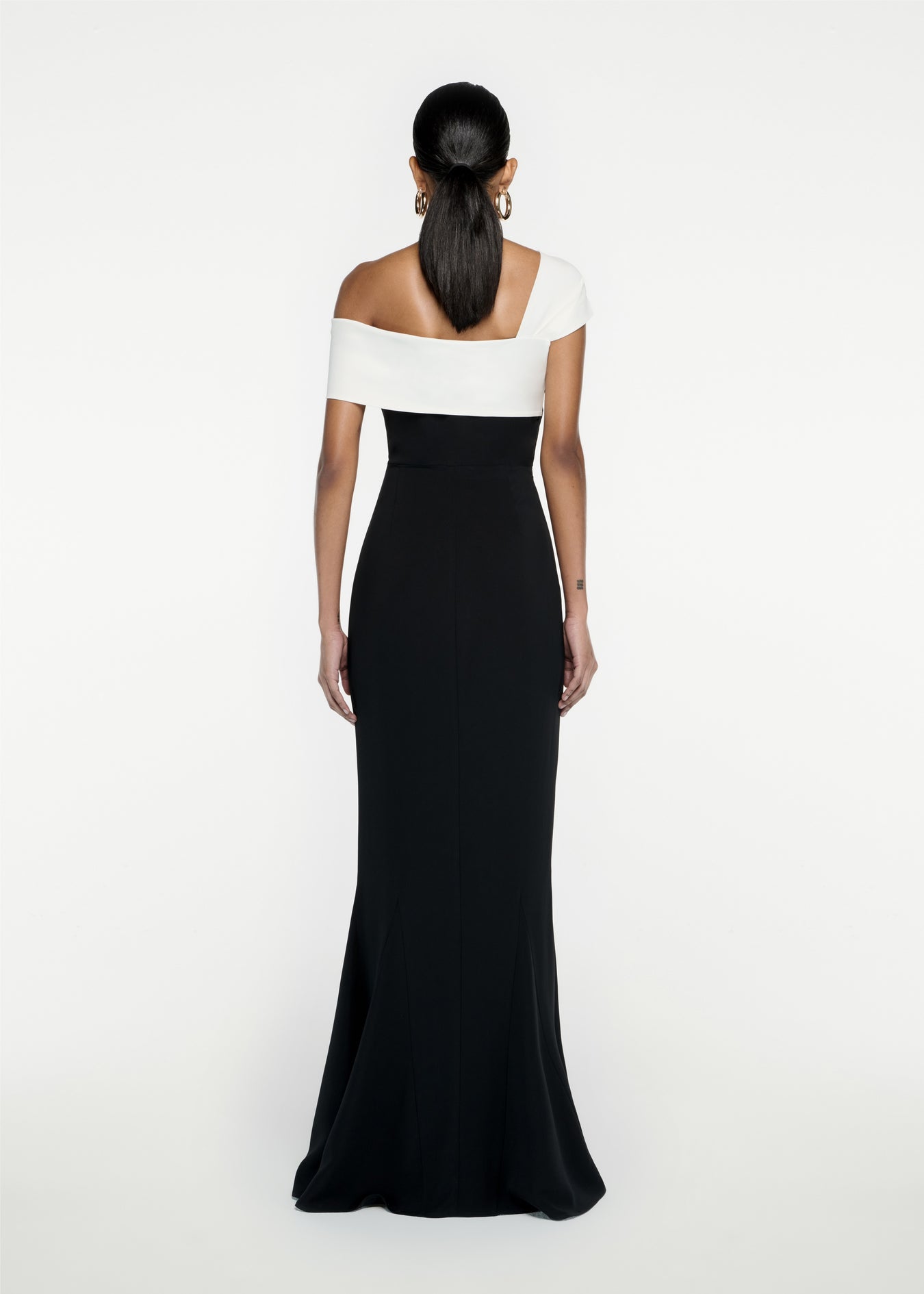 The back of a woman wearing the Asymmetric Stretch Cady Maxi Dress in Monochrome