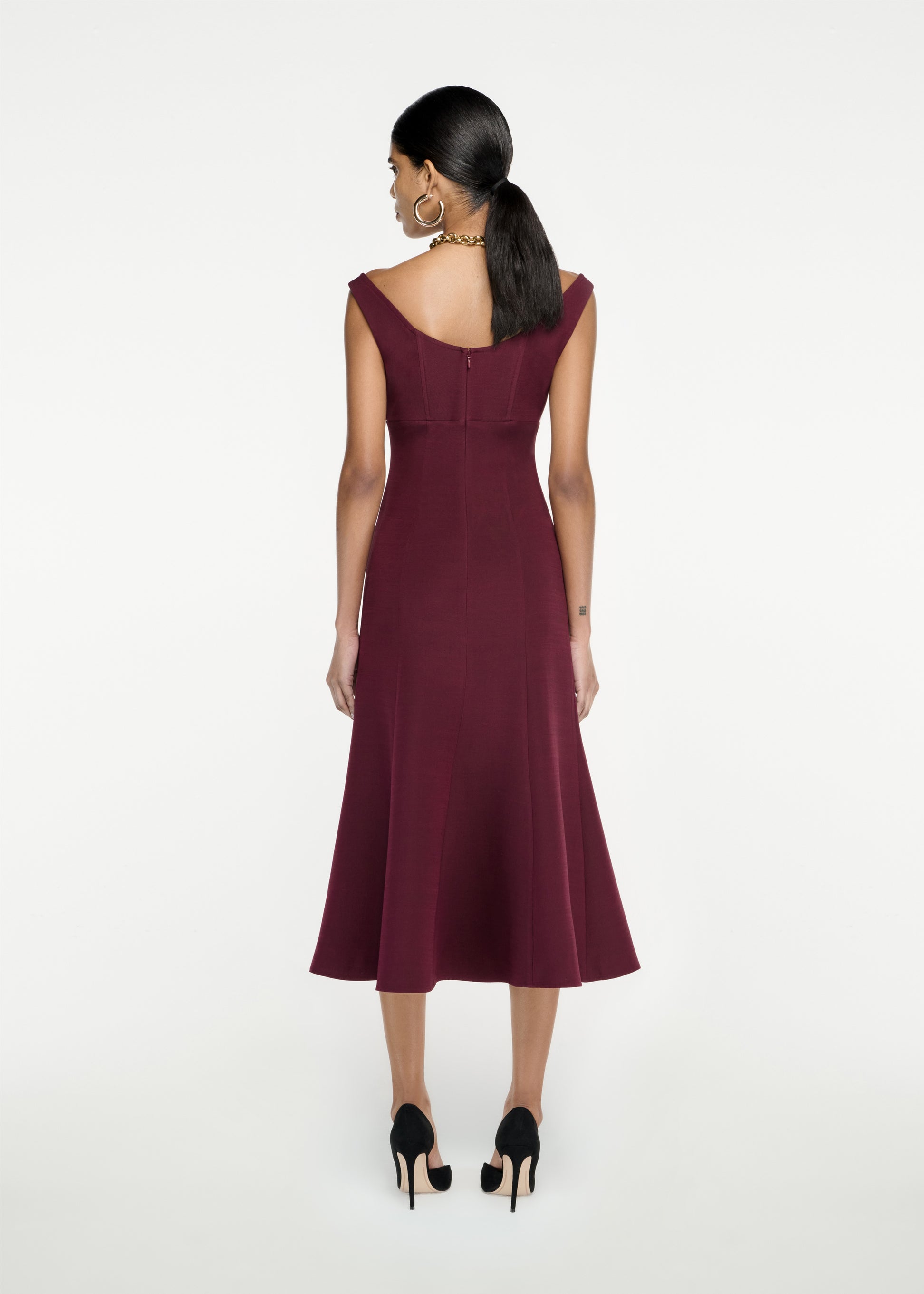 The back of a woman wearing the Off The Shoulder Silk Wool Midi Dress in Maroon
