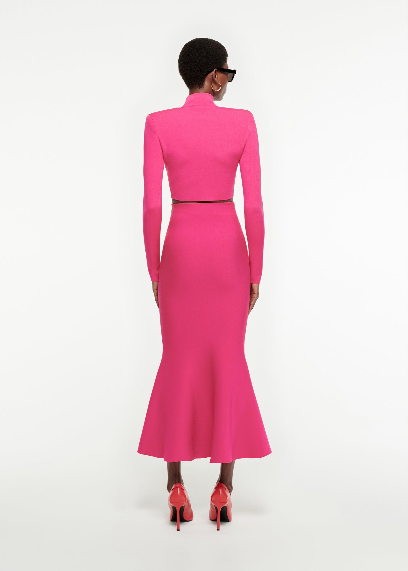The back of a woman wearing the Fluted Knit Midi Skirt in Pink