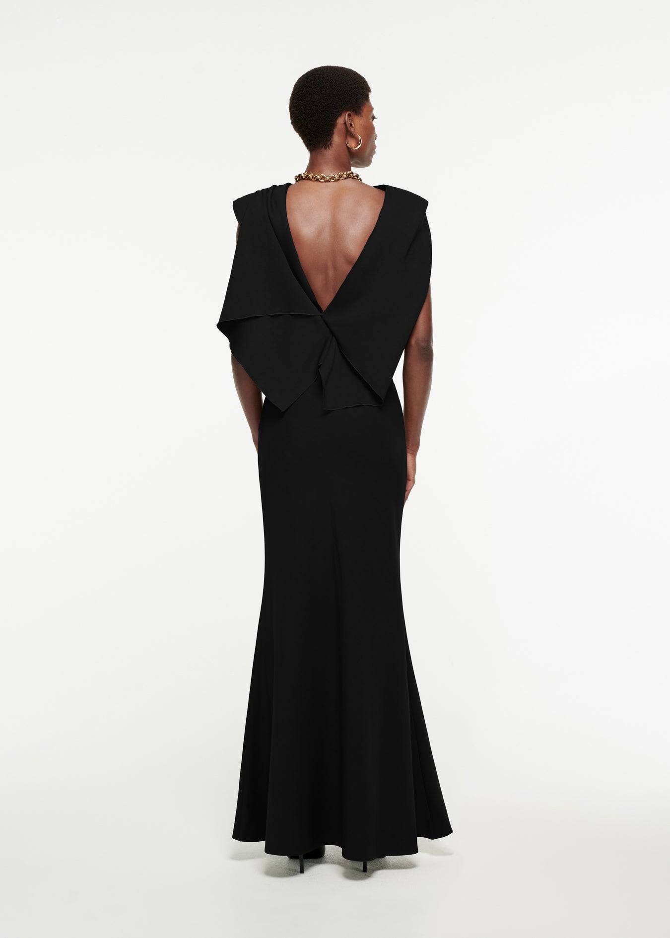 The back of a woman wearing the Draped Stretch-Cady Gown in Black