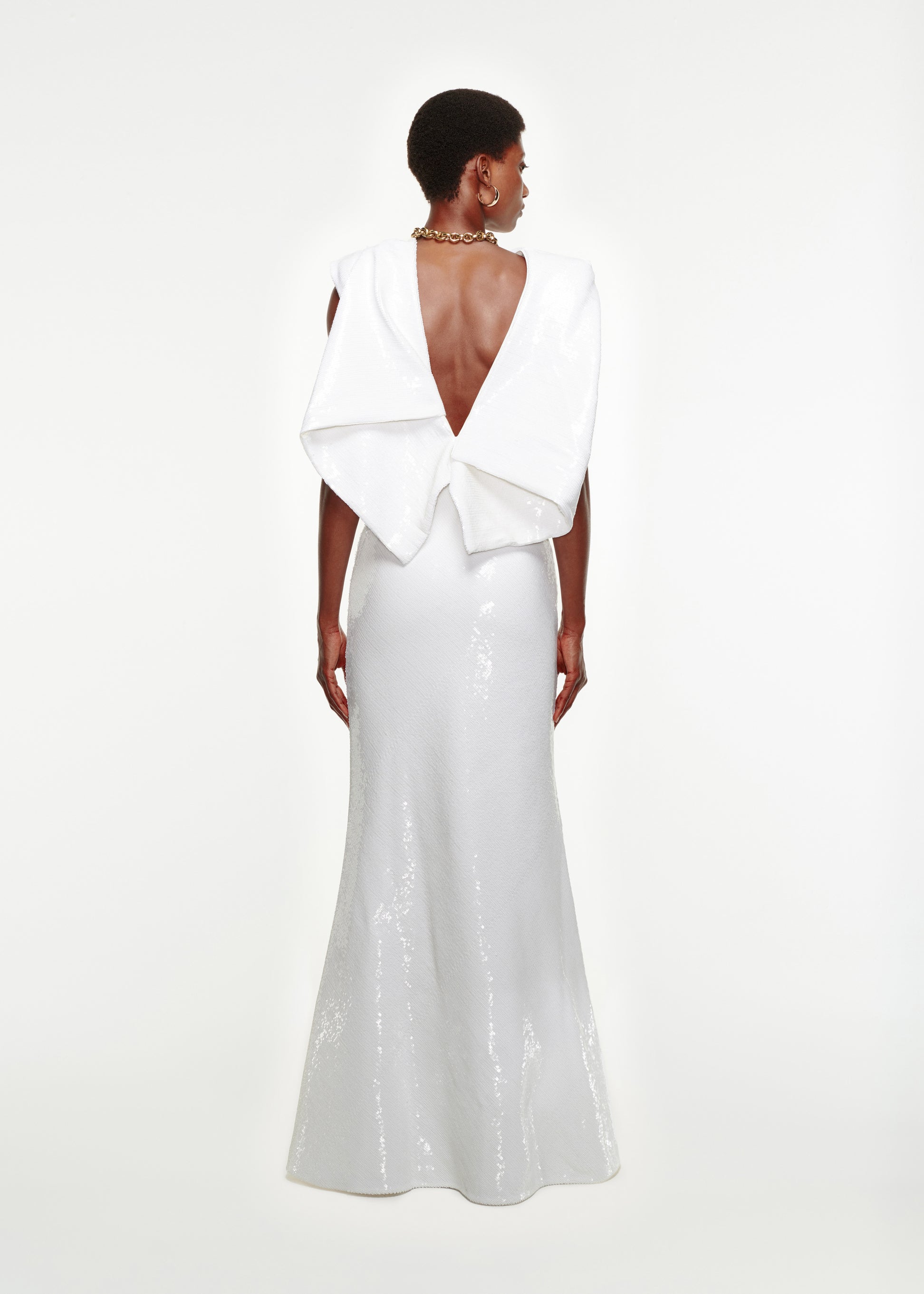 The back of a woman wearing the Draped Sequin Gown in White