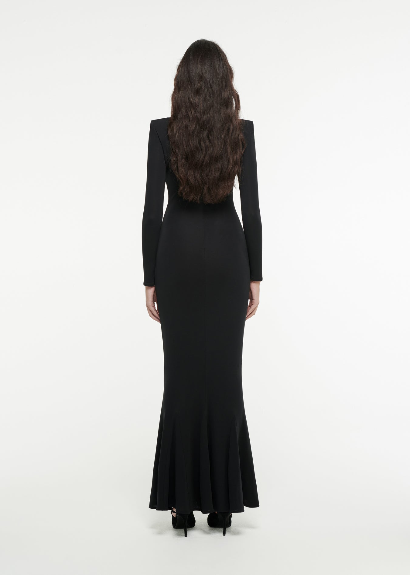 The back of a woman wearing the Long Sleeve Asymmetric Gown in Black 