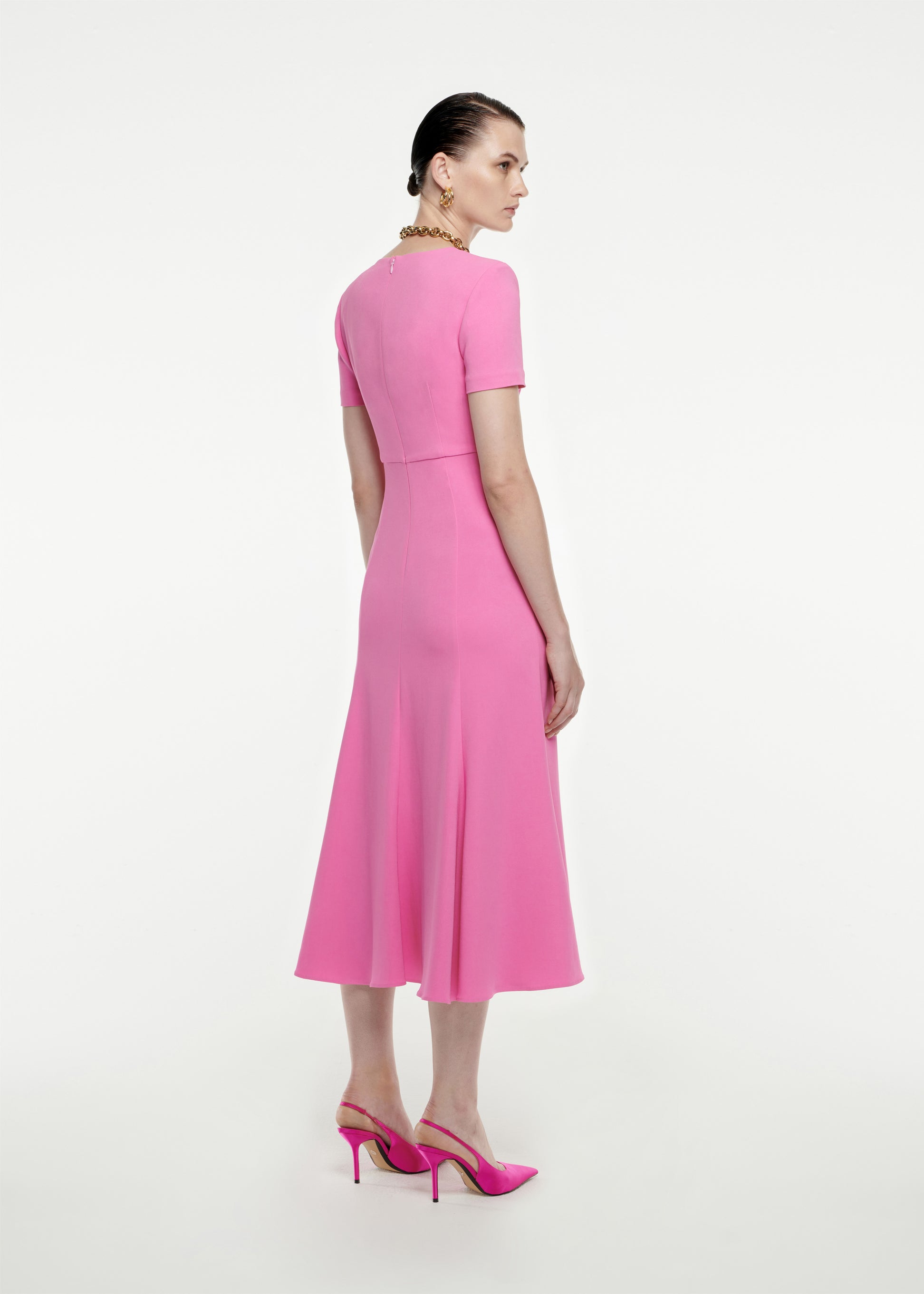 The back of a woman wearing the Short Sleeve Stretch-Cady Midi Dress in Pink