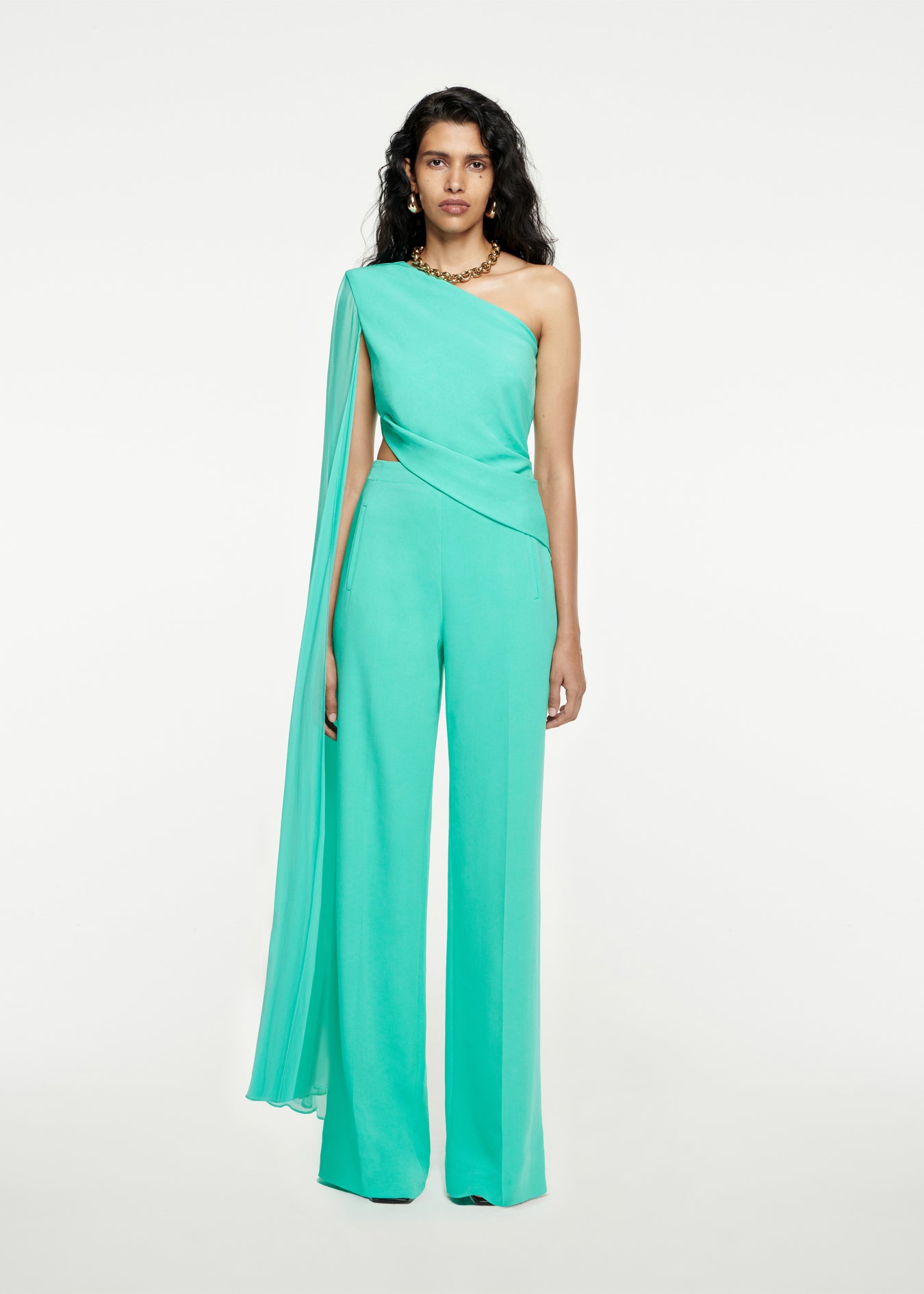 Woman wearing the Asymmetric Stretch-Cady Cape Jumpsuit in Turquoise