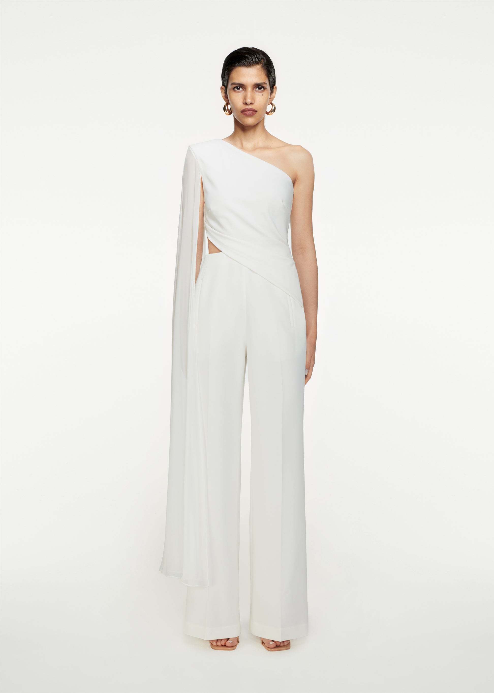 Woman wearing the Asymmetric Stretch-Cady Cape Jumpsuit in White