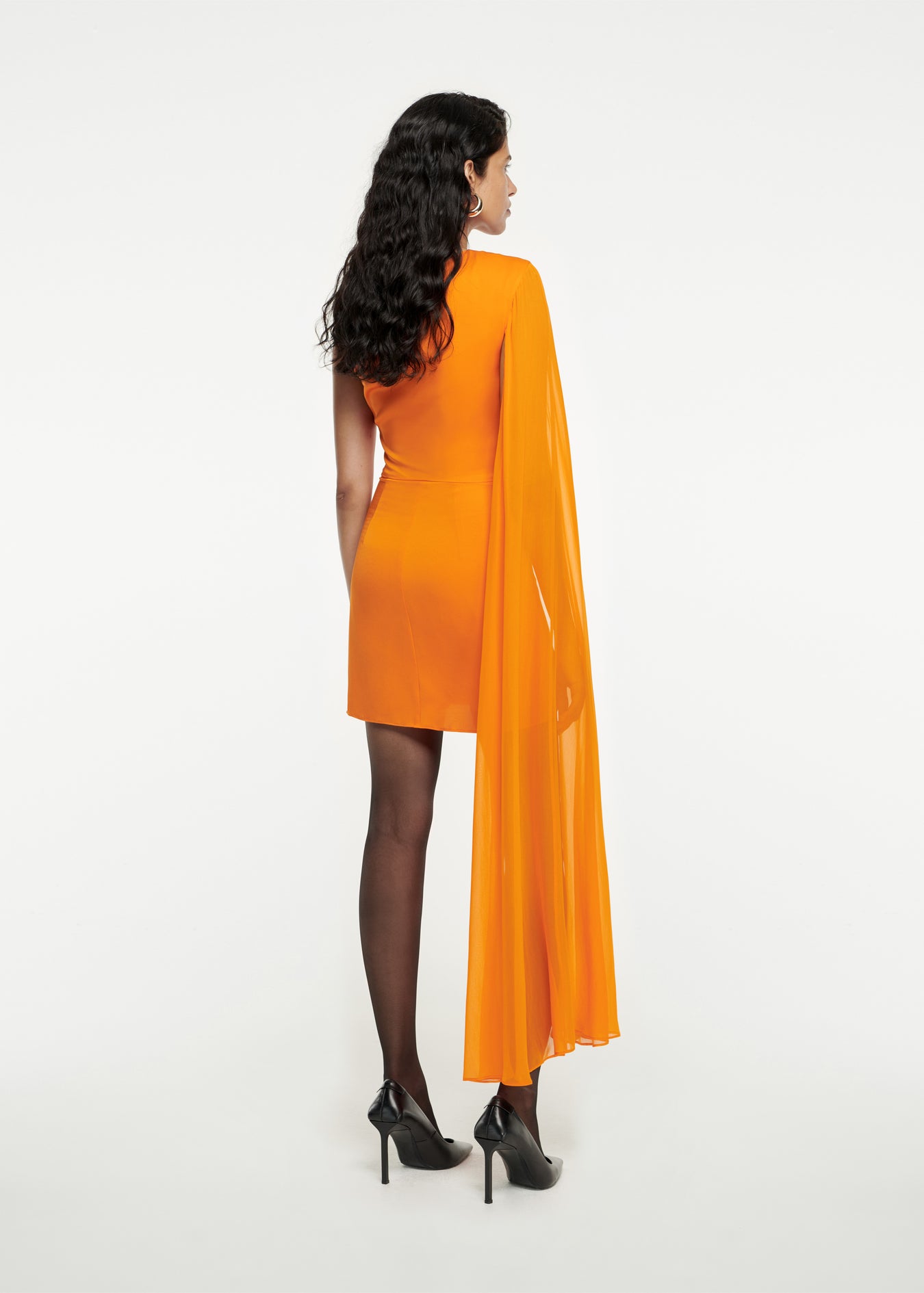 The back of a woman wearing the Asymmetric Stretch Silk Crepe Mini Dress in Orange