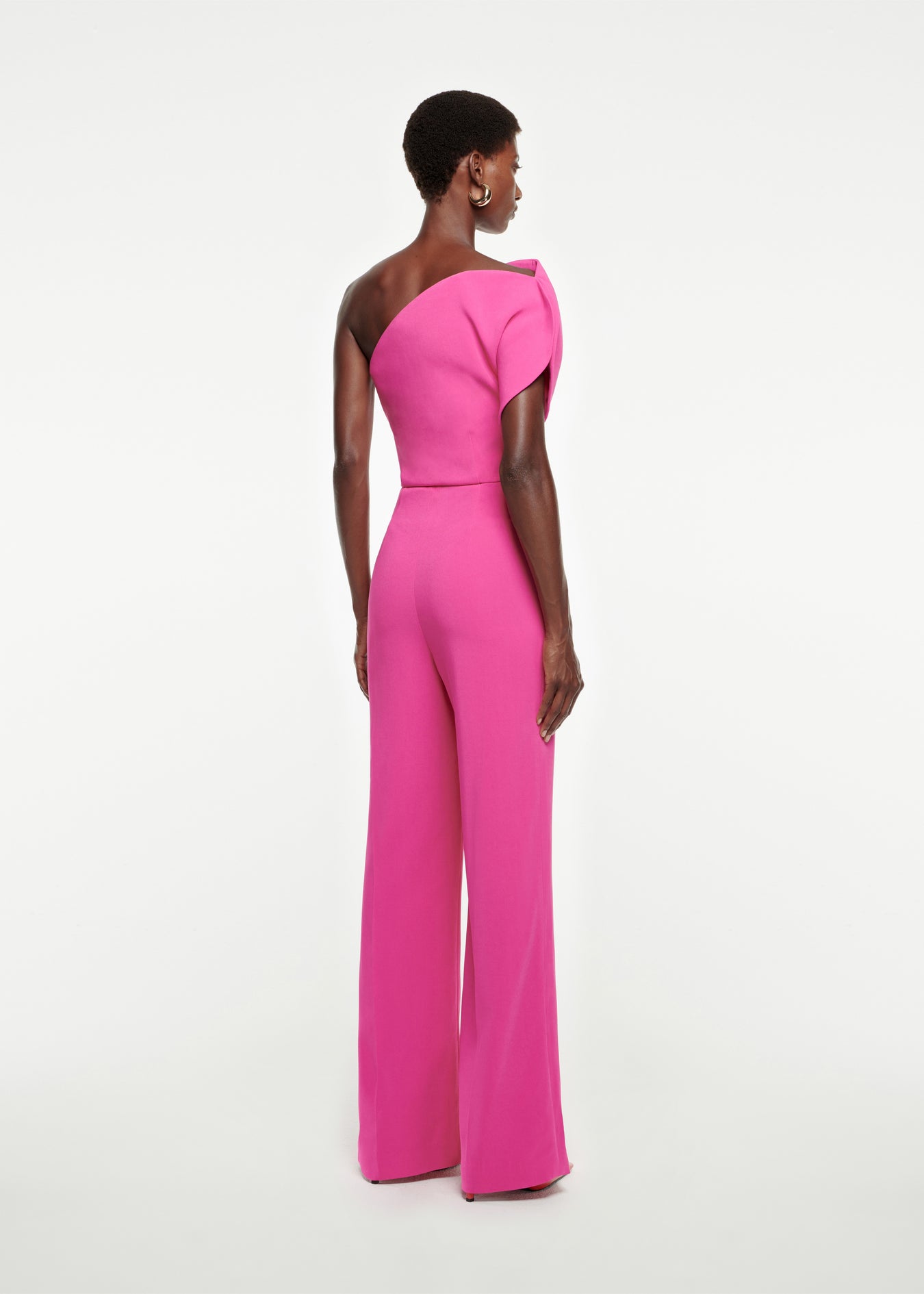 The back of a woman wearing the Asymmetric Stretch-Cady Jumpsuit in Pink