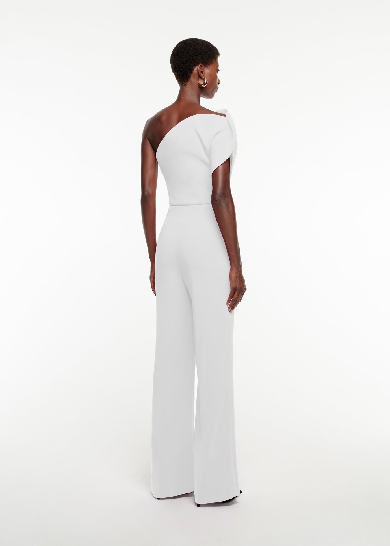 The back of a woman wearing the Asymmetric Stretch-Cady Jumpsuit in White