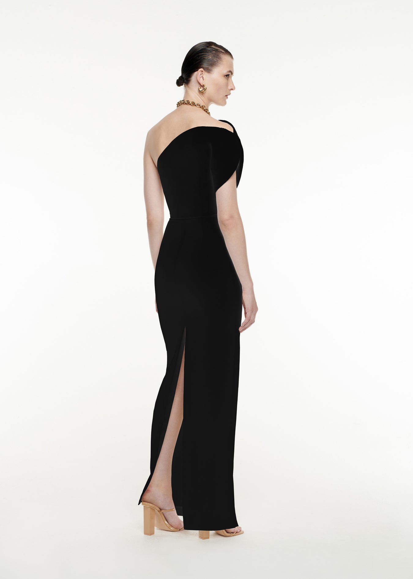 The back of a woman wearing the Asymmetric Silk Wool Maxi Dress in Black