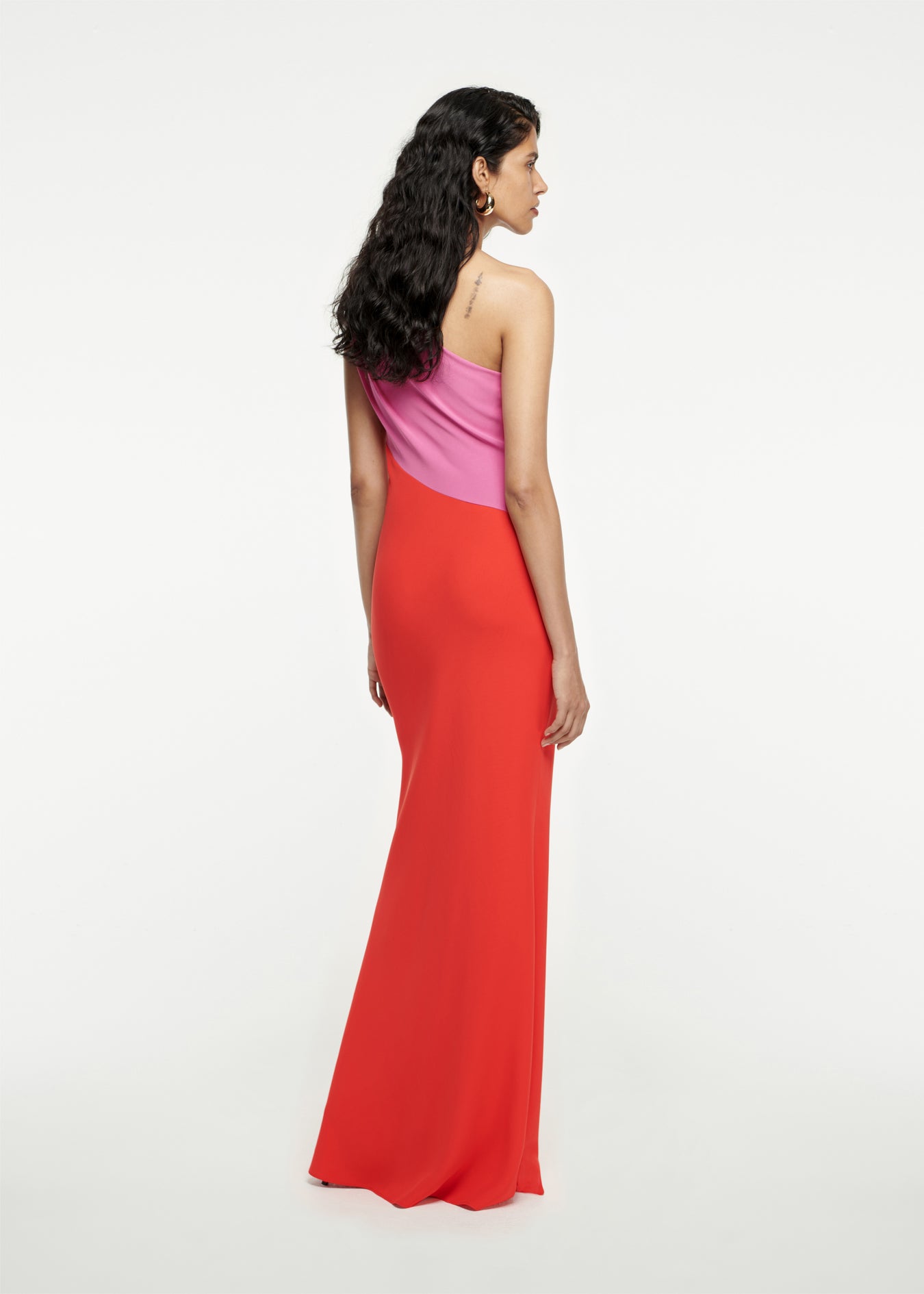 The back of a woman wearing the Asymmetric Stretch-Cady Maxi Dress in Red