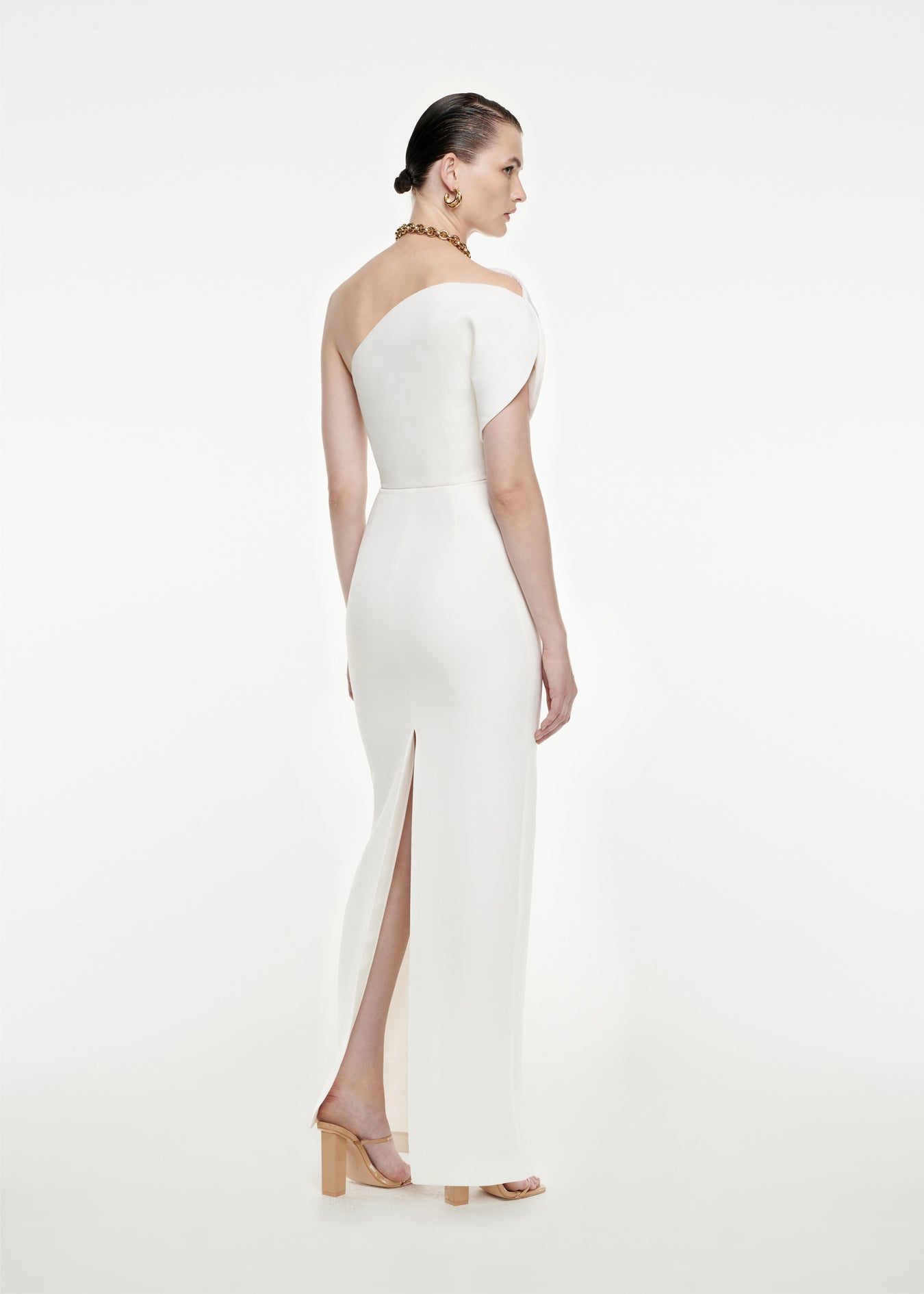 The back of a woman wearing the Asymmetric Silk Wool Maxi Dress in White